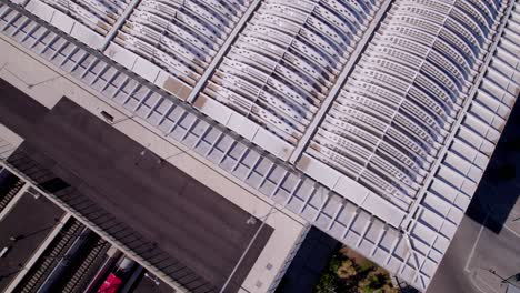 drone shot of a architectural building used as bridge while cars and a transport train go underneath it during sunset