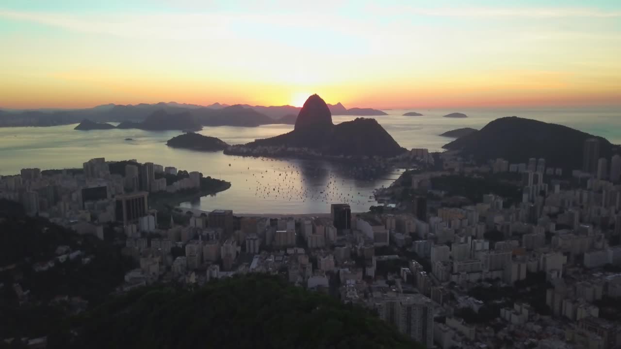 Drone tilt up and pull back above Rio De Janeiro downtown during sunset on the background