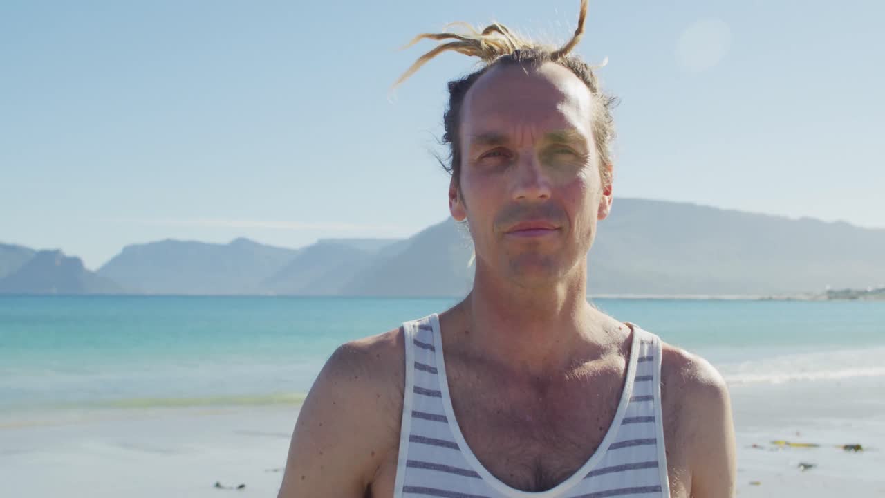 ⁇ 은 해변 에 서 있는 드레드 로크 를 가진 미소 짓는 백인 남성 의 비디오 초상화