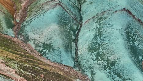 aerial drone close-up, fast movement from bottom to top along the left side of grænihryggur, the green rock, in landmannalaugar, iceland, showcasing medium tones of orange and green