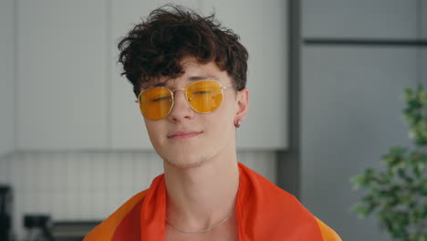 young man wearing pride flag and sunglasses