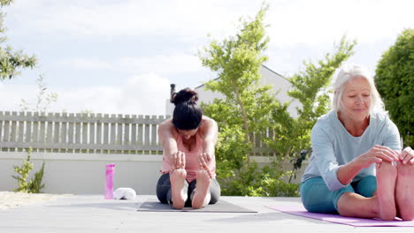 Two-happy-diverse-senior-women-stretching-and-smiling-in-sunny-garden,-slow-motion