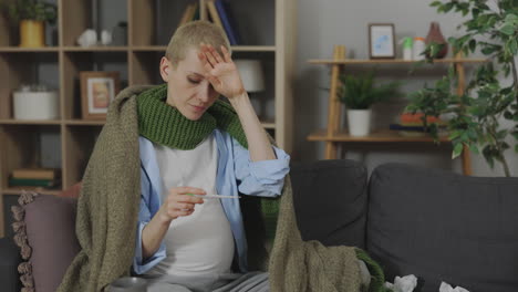 sick pregnant woman taking temperature at home