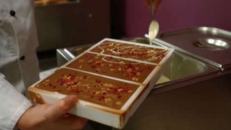 worker drizzling white chocolate on chocolate mould