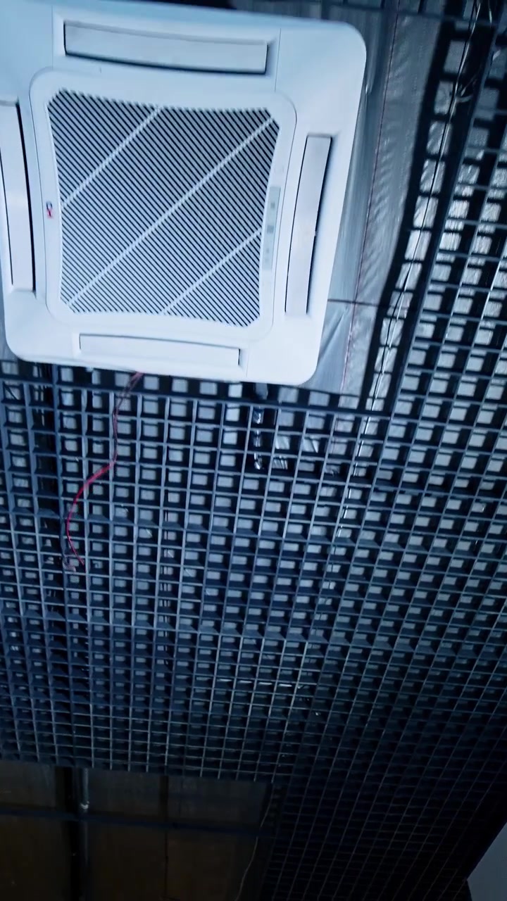 Dark ceiling with grate in the spacious premise. Unfinished room with air conditioner and wires. Low angle view. Vertical video
