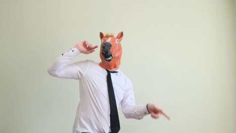 portrait of a strange man in a white shirt a funny horse mask having fun and dancing on background portrait of a strange man in a white shirt a funny horse mask having fun and dancing on an isolated white background fun party humor concept
