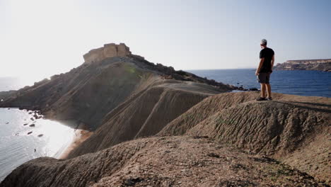 turista caucásico contemplando enormes acantilados de dunas en la isla de malta