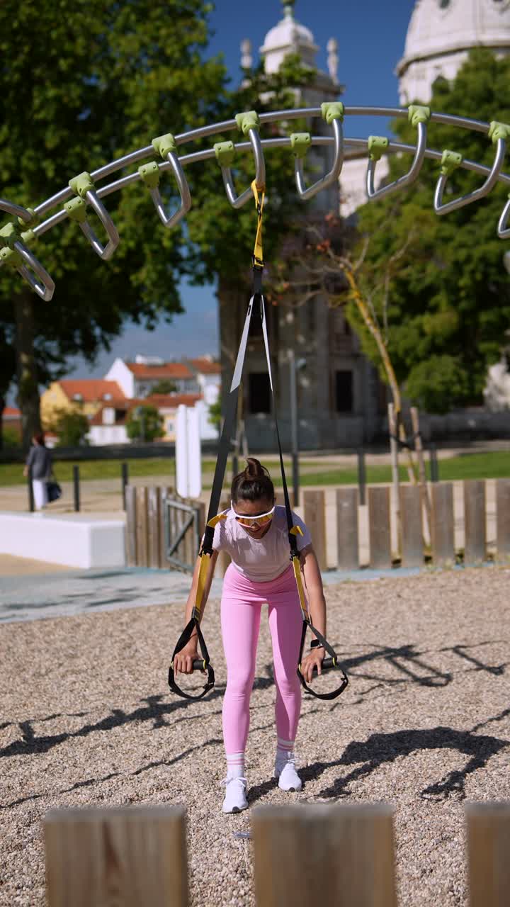 Woman working out in a park using suspension training equipment
