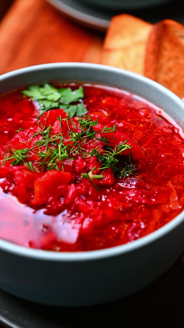 Warm red soup with parsley. Warm red soup decorated with parsley served alongside a small cream dish