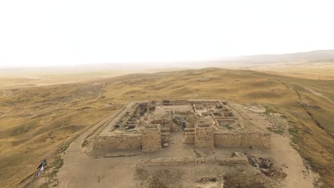 ancient fort ruined at the top of a small mountain in the middle of the desert