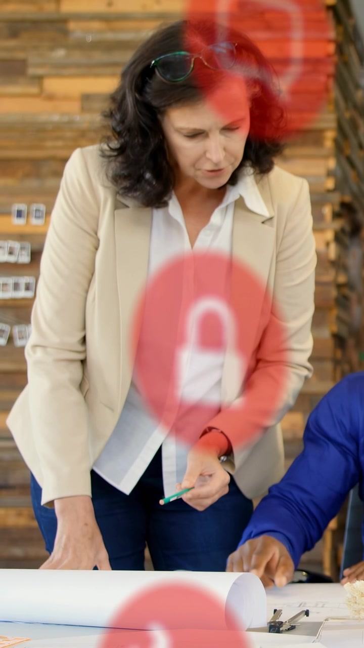 Video verticale: Donna che si china, indicando con una penna verde una planimetria di design, con un lucchetto rosso che oscura.