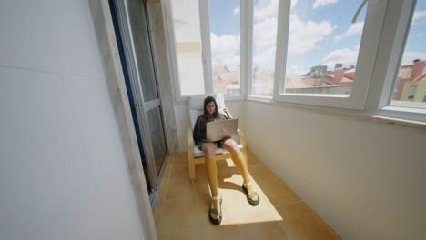 mujer trabajando en una computadora portátil en un balcón