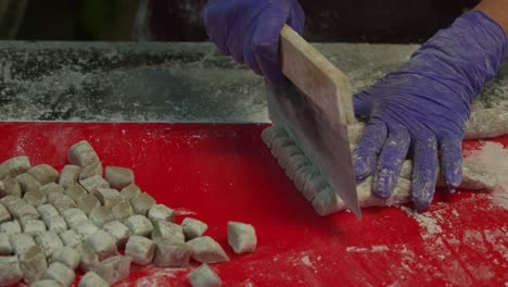 After-rolling-the-taro-dough-into-cylindrical-shapes,-it-is-chopped-using-a-dough-cutter-into-small-portions,-close-up-shot-preparation-of-yam-balls,-the-popular-traditional-Taiwanese-dessert