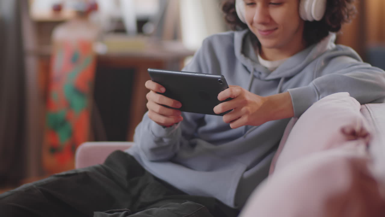 un adolescente alegre jugando a un videojuego en una tableta