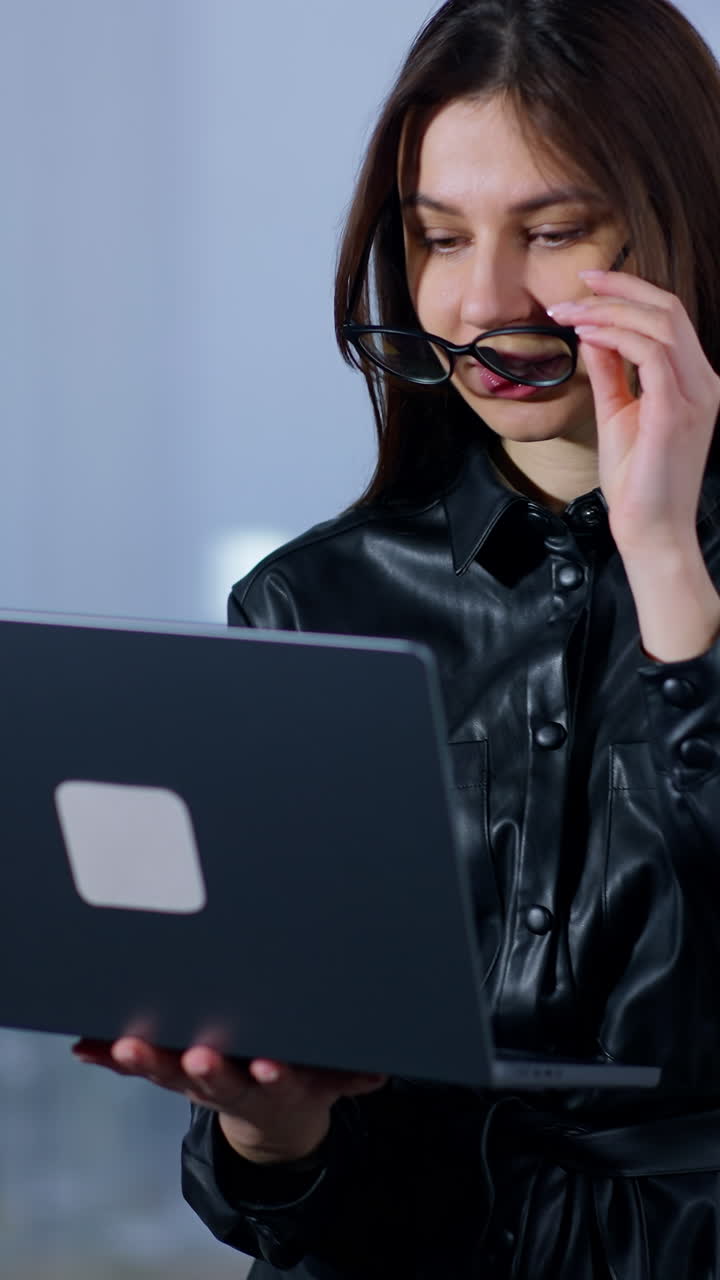 Business lady looking attentively on the screen of laptop. Woman notices something wrong and puts off glasses surprised and bewildered. Vertical video