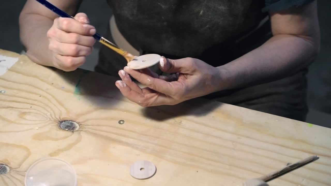 Female artist painting parts of wooden toy