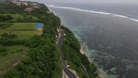 vista aérea, carretera de asfalto a orillas de acantilados y mar ubicada en la playa de tanah barak, isla de bali, indonesia