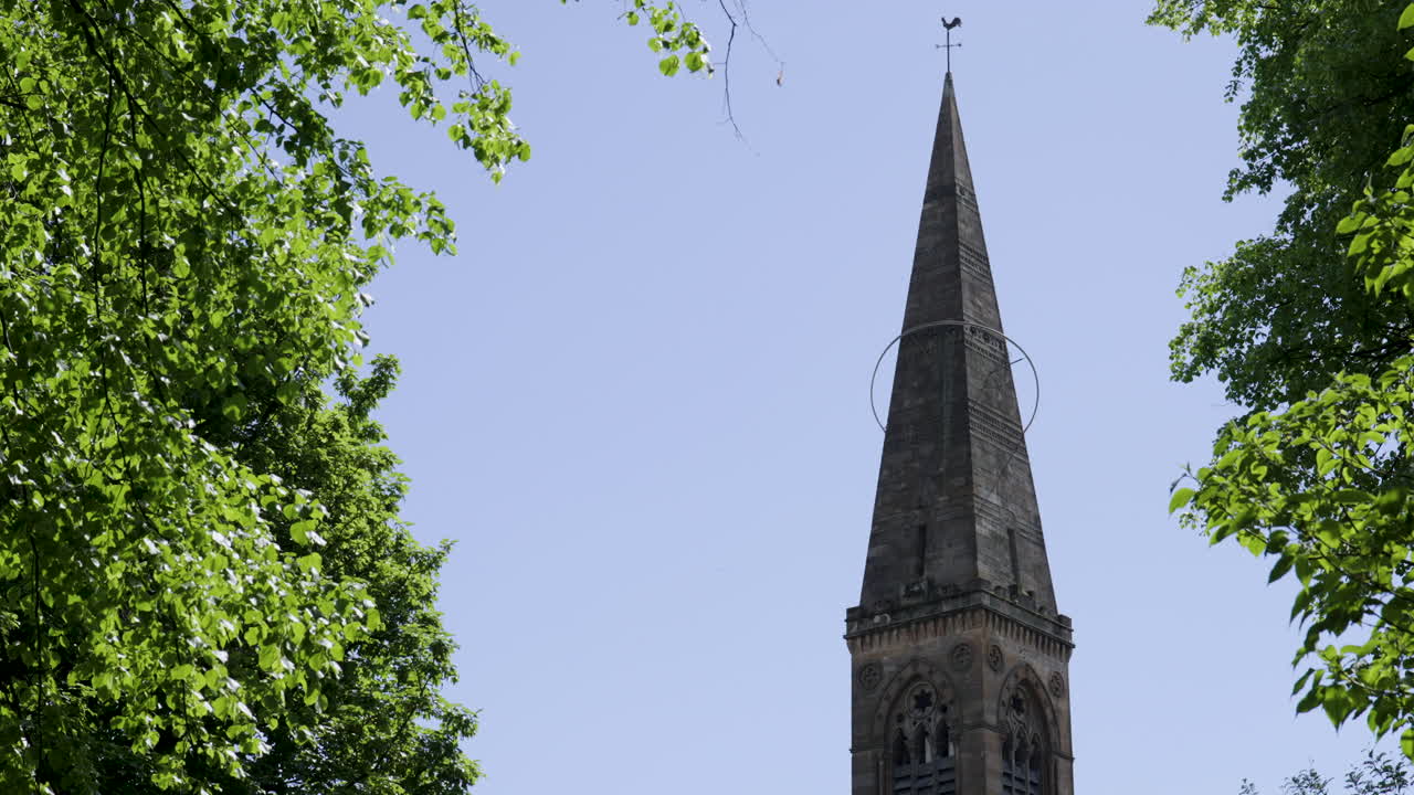 Primo piano del campanile della chiesa di Oran Mor circondato da alberi verdi a Glasgow