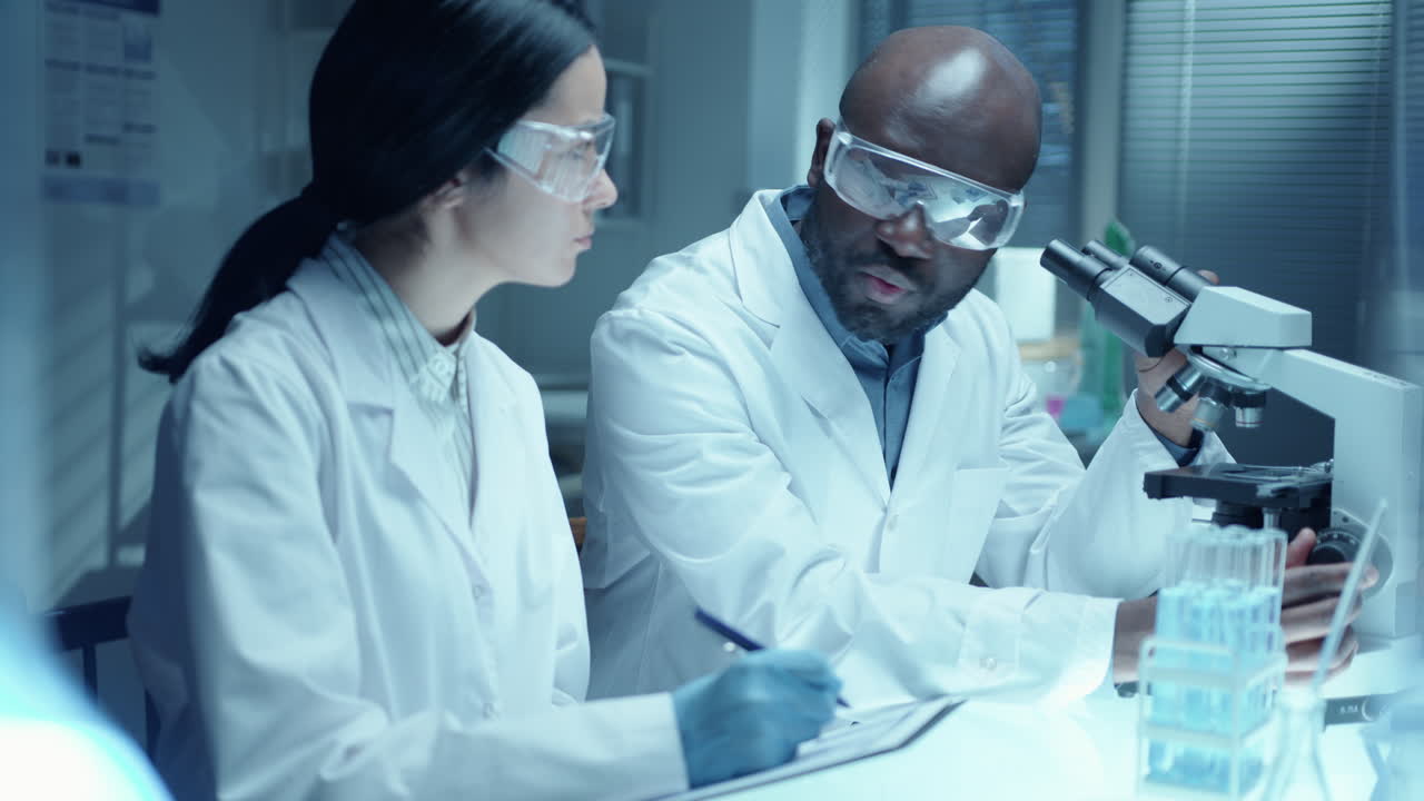 African American Chemist Conducting Research with Assistant in Laboratory