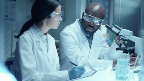 african american chemist conducting research with assistant in laboratory