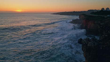 hermosa puesta de sol costera tranquila sobre el océano espumoso salpicando en la costa rocosa aérea