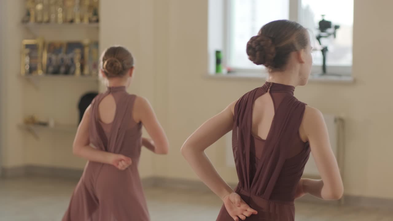 un grupo de jóvenes estudiantes de ballet con ropa de baile negra practicando posiciones en un amplio estudio de ballet con pisos de madera y barras montadas en la pared. expresiones enfocadas y movimientos sincronizados.