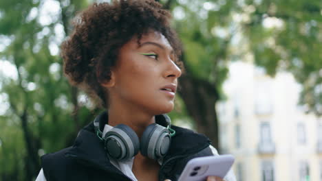 african lady typing smartphone walking city street closeup. woman using phone