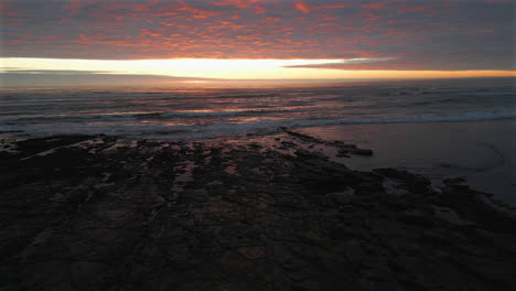 Descenso-Estableciendo-Un-Drone-Aéreo-Disparado-Sobre-La-Playa-Al-Amanecer-En-North-Yorkshire-Durante-La-Marea-Baja,-Reino-Unido