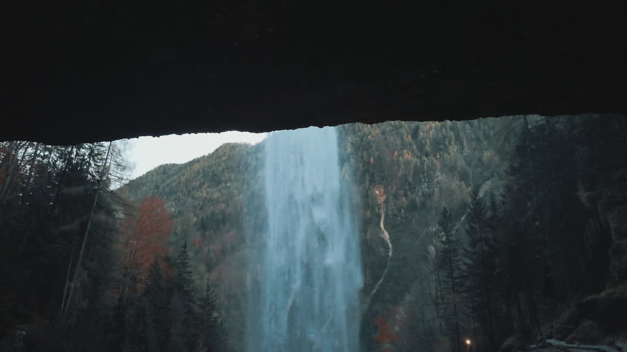 Powerful Pericnik Waterfall flowing in autumn forest. Waterfall plunging down a rocky cliff in a dark, moody autumn forest in Slovenia
