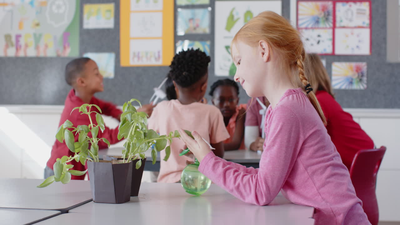 In school, girl watering plant with spray bottle in classroom, other kids talking