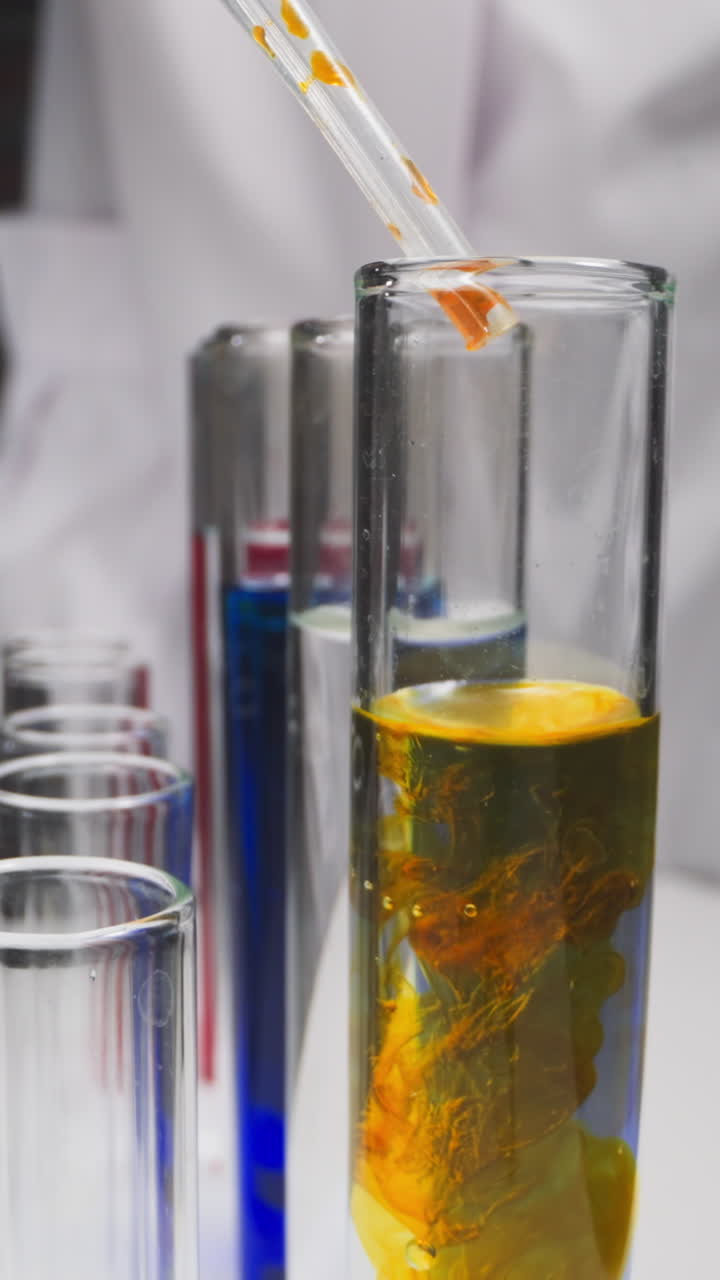 Lab assistant drips yellow liquid into test tube with reagent in chemical workshop slow motion. Probe lens shot of scientific experiment closeup