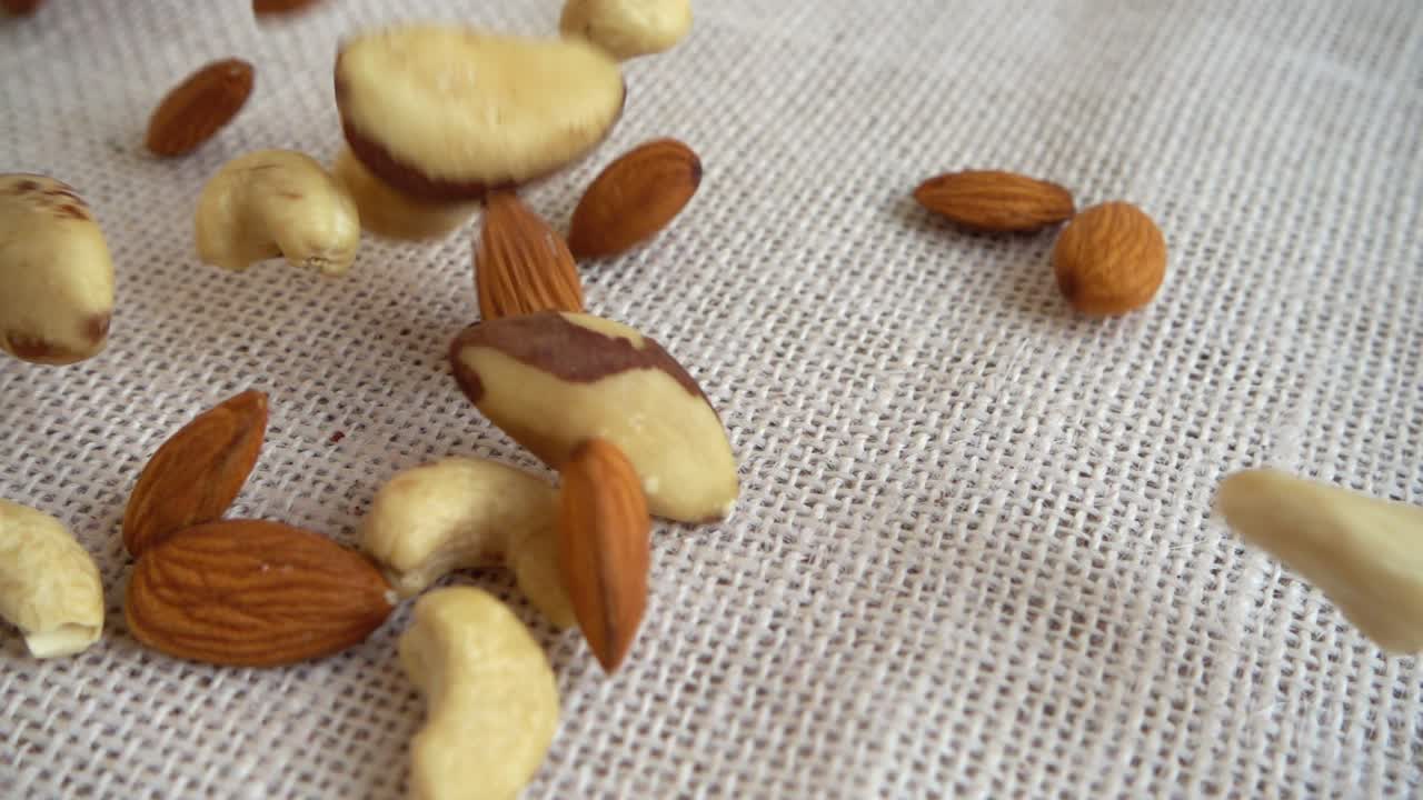 Almonds nuts, cashews nuts, Brazil nuts and hazelnut nuts. Shooting while falling on a sack. Slow motion