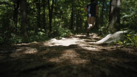 un joven corriendo más allá de la cámara en el camino del bosque