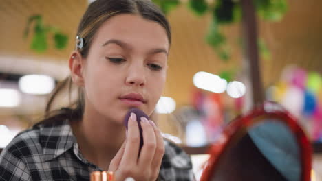 joven mezclando cuidadosamente el maquillaje en la mandíbula usando esponja de belleza para una aplicación suave, centrada en lograr una complexión uniforme con un acabado suave y natural, en un entorno interior con iluminación cálida