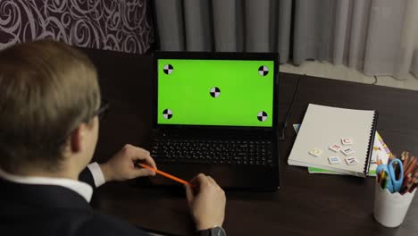 hombre haciendo una llamada de video en línea en una computadora portátil. pantalla verde. educación a distancia