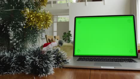 Laptop-with-green-screen-copy-space-on-table-at-home,-with-decorated-christmas-tree