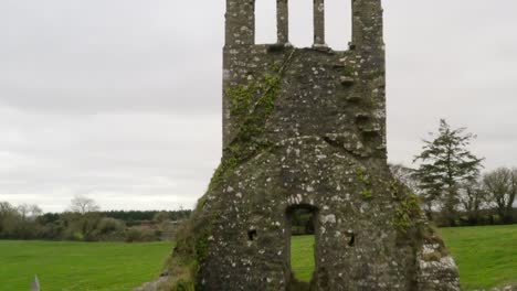 Drone-descends-pullback-along-old-mossy-bell-tower-and-church-wall-remnants