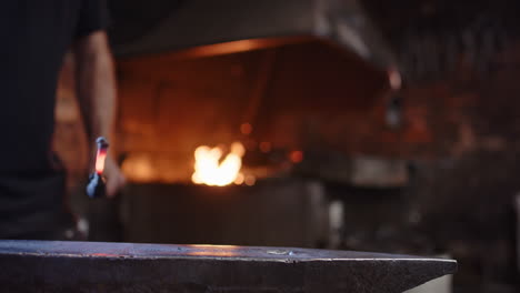 blacksmith brings hot iron from the forge to the anvil for hammering, smithy
