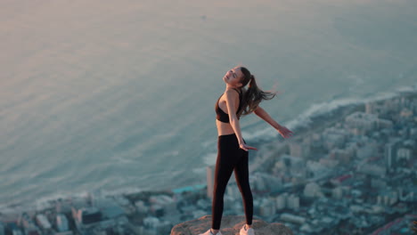 Junge-Frau-Mit-Erhobenen-Armen-Auf-Dem-Berggipfel-Feiert-Leistung-Mädchen-Am-Rande-Einer-Klippe-Blickt-Auf-Die-Wunderschöne-Aussicht-Bei-Sonnenuntergang-Und-Genießt-Das-Reiseabenteuer