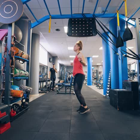 pretty girl jumping in the gym. active young woman in sporty wear imitating jumps on a skipping rope at fitness centre.