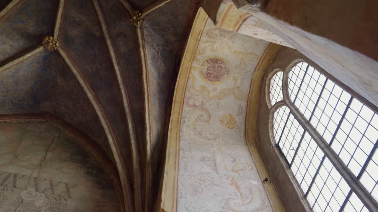 A tall, pointed window set into a thick, massive wall of a Gothic castle