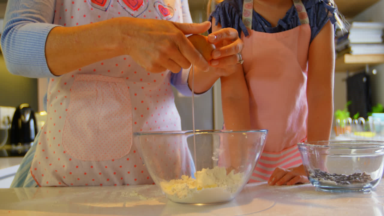 vista frontal de la madre y la hija horneando galletas en la cocina de una casa cómoda 4k
