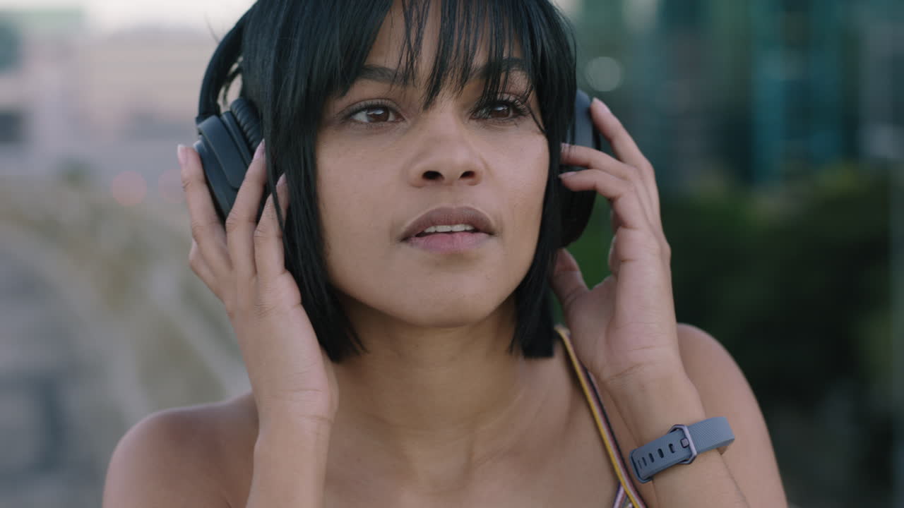retrato en primer plano hermosa joven mujer hispana con auriculares escuchando música sonriendo feliz disfrutando del estilo de vida urbano mirando con confianza a la cámara