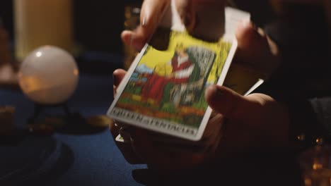 primer plano de una mujer barajando o cortando cartas para la lectura del tarot en la mesa 1 a la luz de las velas