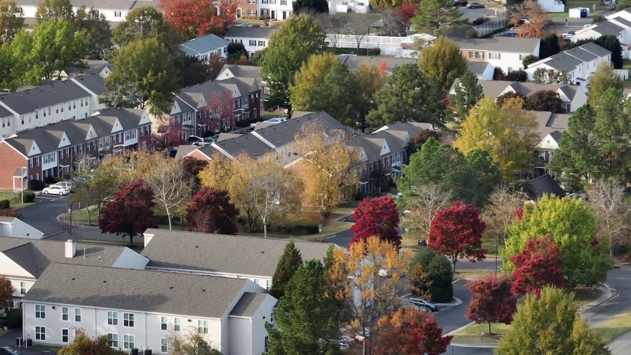 Magnificent neighborhood of America in fall season. Townhouses and row houses between multi-colored trees in autumn. Aerial wide shot. Peaceful scene in quiet suburbia of Virginia