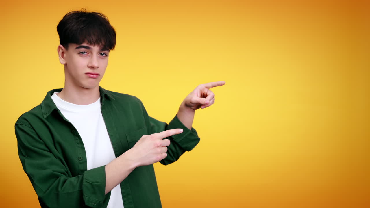 Serious young man showing next to him and sign of refusal on a yellow background