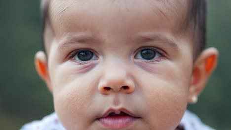 close up of a toddler blinking big blue eyes, revealing noticeable dark circles underneath. the expression captures a mix of curiosity and innocence in a natural indoor setting