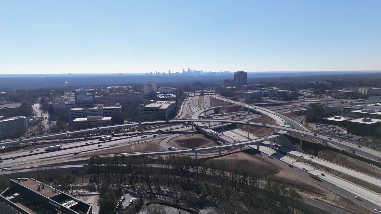 Static drone shot of GA-400 and I-285 traffic with the Atlanta Skyline in the background.