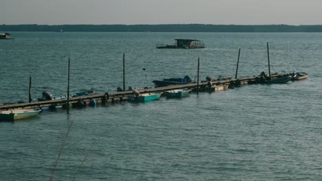 motorboats tied to a wooden dock on the waves of malaysia - wide shot