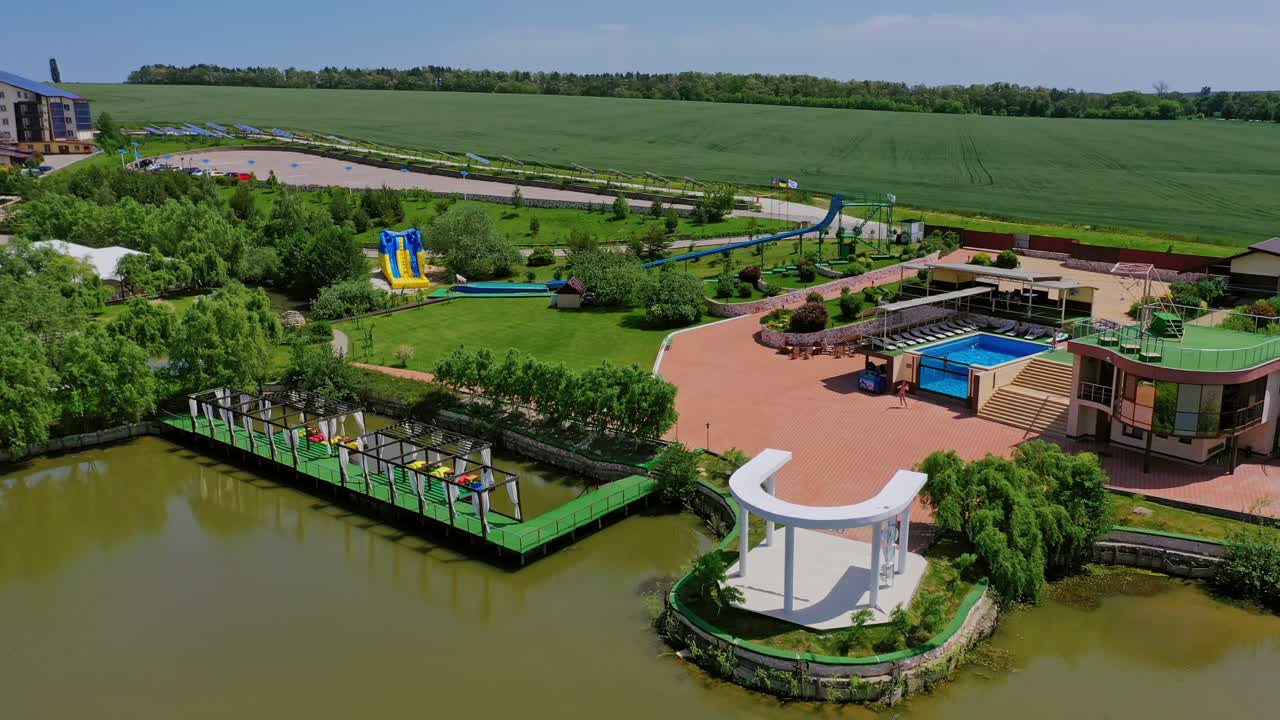 Modern recreation complex near the river. Park with relaxing area on the background of nature in summer. Aerial view.